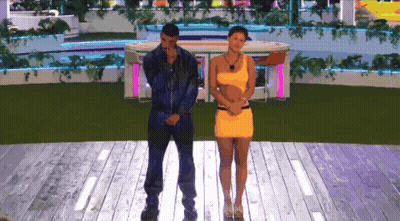 A Man And A Woman Are Standing On A Stage GIF