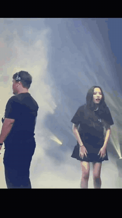 A Man And A Woman Are Standing On A Stage In Front Of A Crowd . GIF