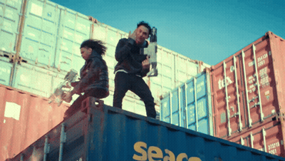 A Man And A Woman Are Standing On Top Of A Seaco Shipping Container GIF