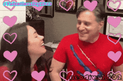 A Man And A Woman Are Surrounded By Pink Hearts With Valentines Day 2022 Written On The Bottom GIF
