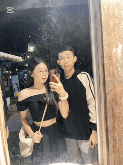 A Man And A Woman Are Taking A Picture In A Mirror GIF