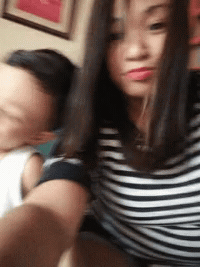 A Man And A Woman Are Taking A Selfie Together . The Woman Is Wearing A Striped Shirt . GIF