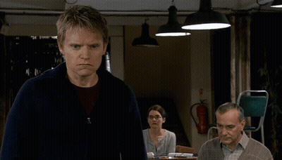 A Man And A Woman Are Talking In Front Of A Door That Has The Word Odds On It GIF