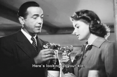 A Man And A Woman Are Toasting With Wine Glasses . The Man Is Holding A Bottle Of Wine . GIF