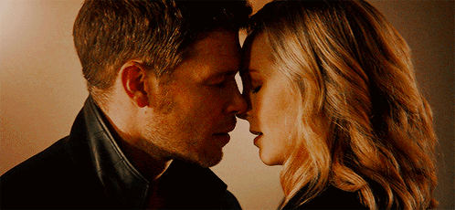 A Man And A Woman Are Touching Their Foreheads GIF