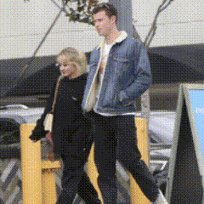 A Man And A Woman Are Walking Down The Street GIF
