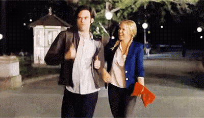 A Man And A Woman Are Walking Down The Street At Night Holding Hands GIF