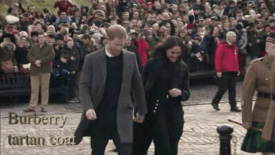 A Man And A Woman Are Walking In Front Of A Crowd Wearing A Burberry Tartan Coat GIF