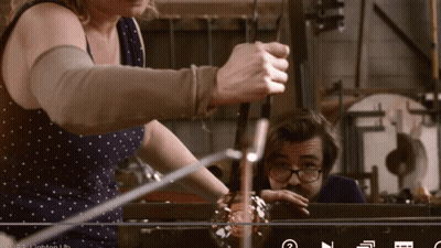 A Man And A Woman Are Working On A Glass Sculpture GIF
