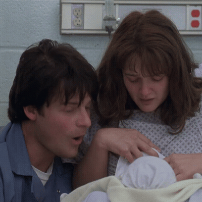 A Man And A Woman Holding A Baby In A Hospital Room GIF