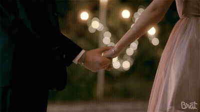 A Man And A Woman Holding Hands With The Word Brat On The Bottom Right GIF