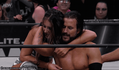 A Man And A Woman Hugging In A Wrestling Ring With The Aew Logo On The Bottom GIF