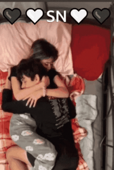 A Man And A Woman Hugging In Bed With The Words " Sn " On The Bottom GIF