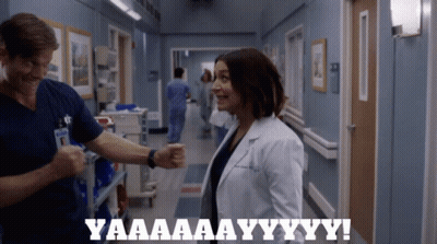 A Man And A Woman In A Hospital Hallway With The Words Yaaaa Aay Yy Yy GIF