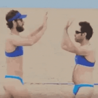 A Man And A Woman In Bikinis Are Walking On A Beach . GIF