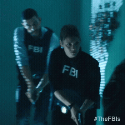 A Man And A Woman In Fbi Uniforms Are Standing In A Dark Room GIF