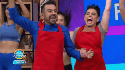 A Man And A Woman In Red Aprons Are Dancing In Front Of A Sign That Says 12:07 Pm GIF
