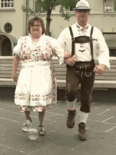 A Man And A Woman In Traditional Costume Are Dancing Together GIF