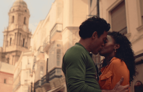 A Man And A Woman Kiss In Front Of A Building GIF