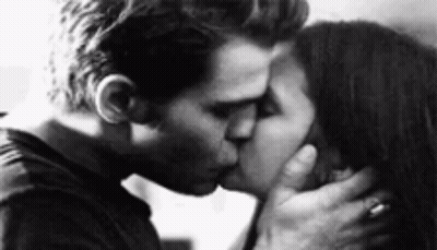 A Man And A Woman Kissing In A Black And White Photo . GIF