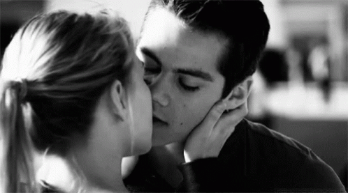 A Man And A Woman Kissing In A Black And White Photo . GIF