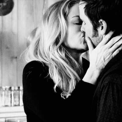 A Man And A Woman Kissing In A Black And White Photo GIF
