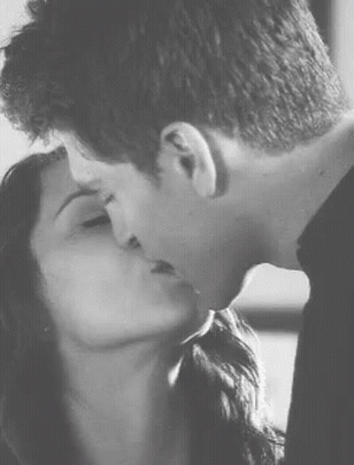 A Man And A Woman Kissing In A Black And White Photo . GIF
