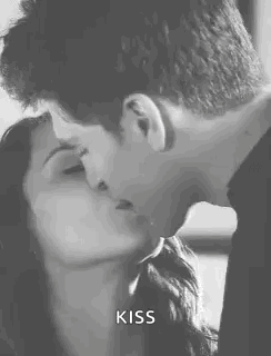 A Man And A Woman Kissing In A Black And White Photo . GIF