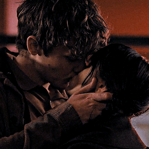A Man And A Woman Kissing In A Dark Room GIF