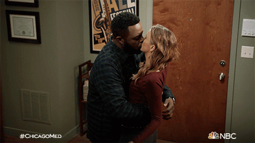 A Man And A Woman Kissing In Front Of A Door With #Chicagomed Written On The Bottom GIF