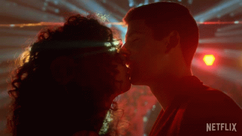 A Man And A Woman Kissing In Front Of A Netflix Sign GIF
