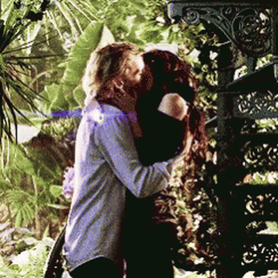 A Man And A Woman Kissing In Front Of A Staircase GIF