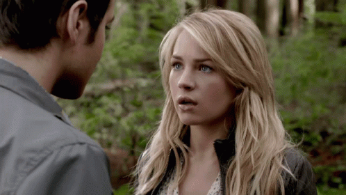 A Man And A Woman Looking At Each Other In The Woods GIF