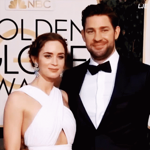 A Man And A Woman Pose For A Picture In Front Of A Sign That Says Nbc GIF