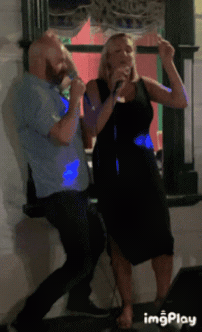 A Man And A Woman Singing Into Microphones In Front Of A Window With Imgplay At The Bottom GIF