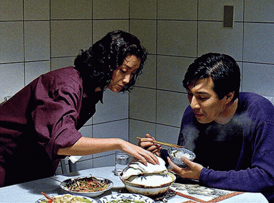 A Man And A Woman Sit At A Table Eating Food GIF