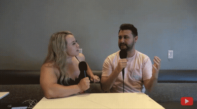 A Man And A Woman Sit At A Table With Microphones GIF