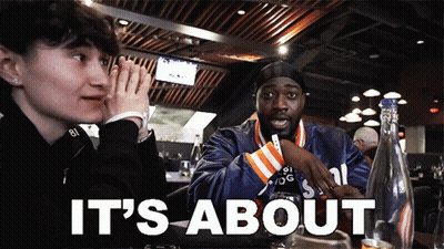 A Man And A Woman Sit At A Table With The Words It 'S About GIF
