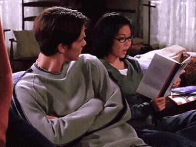 A Man And A Woman Sit On A Couch Reading Books GIF