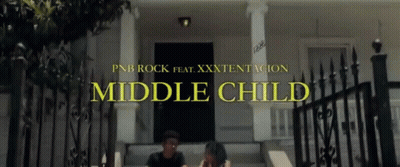 A Man And A Woman Sit On The Steps Of A House With The Words Middle Child Written Above Them GIF