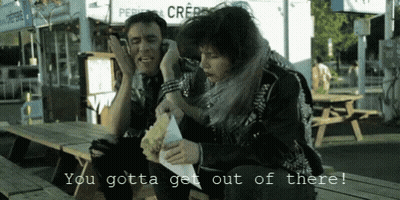 A Man And A Woman Sitting At A Picnic Table With The Words You Gotta Get Out Of There On The Bottom GIF