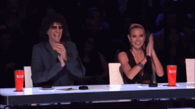 A Man And A Woman Sitting At A Table Clapping GIF
