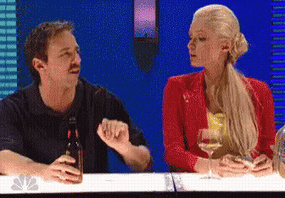 A Man And A Woman Sitting At A Table With A Bottle Of Beer And A Glass Of Wine GIF