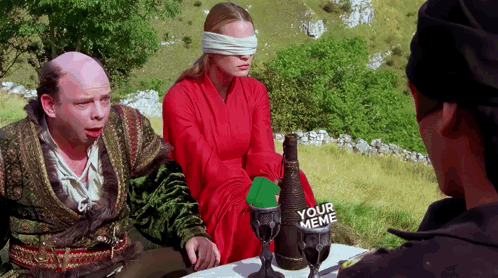 A Man And A Woman Sitting At A Table With A Bottle Of Your Meme On It GIF