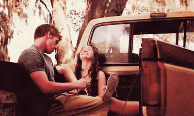A Man And A Woman Sitting In The Back Of A Truck GIF