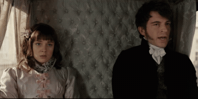 A Man And A Woman Sitting Next To Each Other In A Room GIF