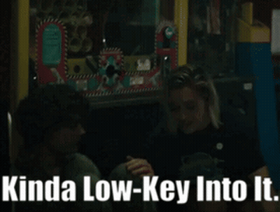 A Man And A Woman Sitting Next To Each Other With Kinda Low-Key Into It Written On The Bottom GIF
