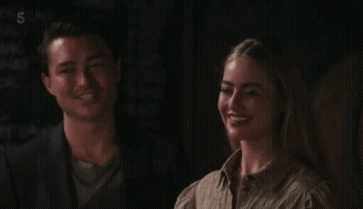 A Man And A Woman Sitting Next To Each Other With The Number 5 On The Bottom Left GIF