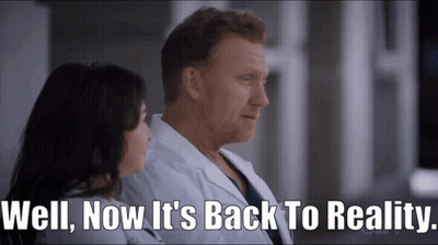 A Man And A Woman Sitting Next To Each Other With The Words Well Now It 'S Back To Reality Written Below Them GIF