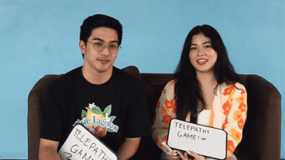 A Man And A Woman Sitting On A Couch Holding Up Signs That Say Telepathy Game GIF